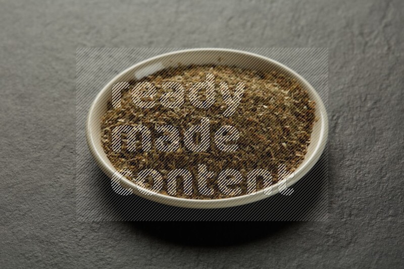 white ceramic round sauce dish filled with herbs on grey textured countertop