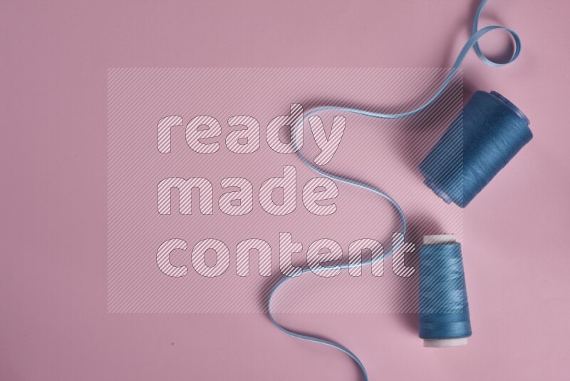 A blue collection of sewing and tailoring tools arranged on a pink background