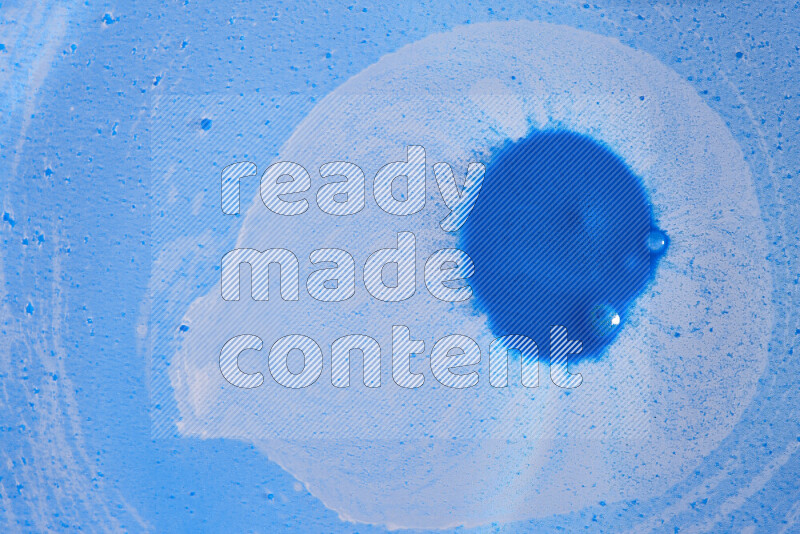 The image captures a dramatic splatter of blue paint over a blue backdrop