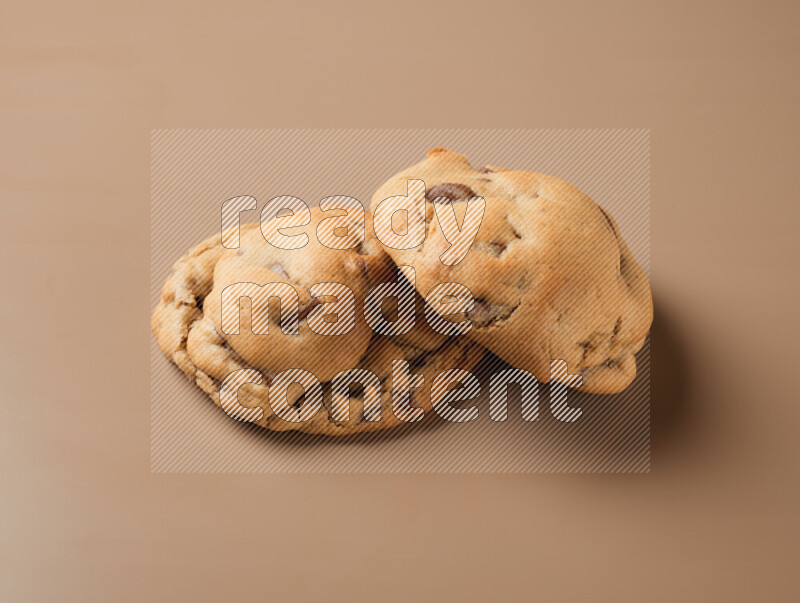Two chocolate chip cookies on a brown background