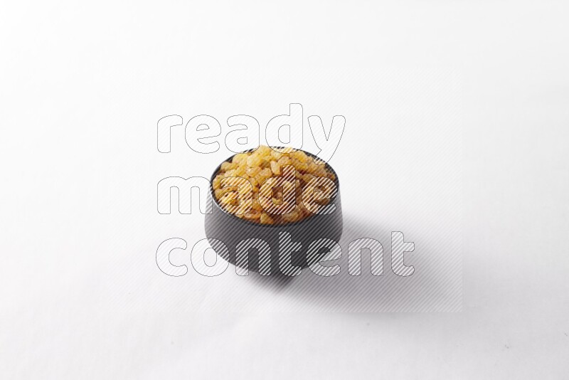 Raisins in a black pottery bowl on white background