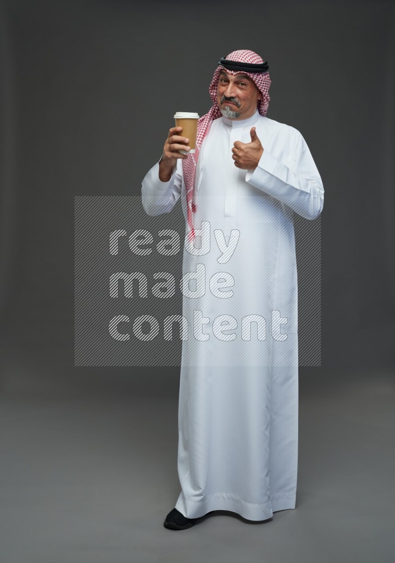 Saudi man with shomag Standing holding paper cup on gray background