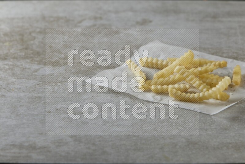 crinkle fries on parchment paper on grey textured counter top