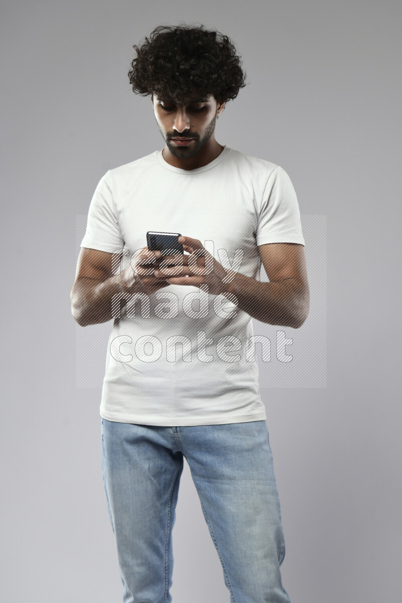 A man wearing casual standing and texting on the phone on white background