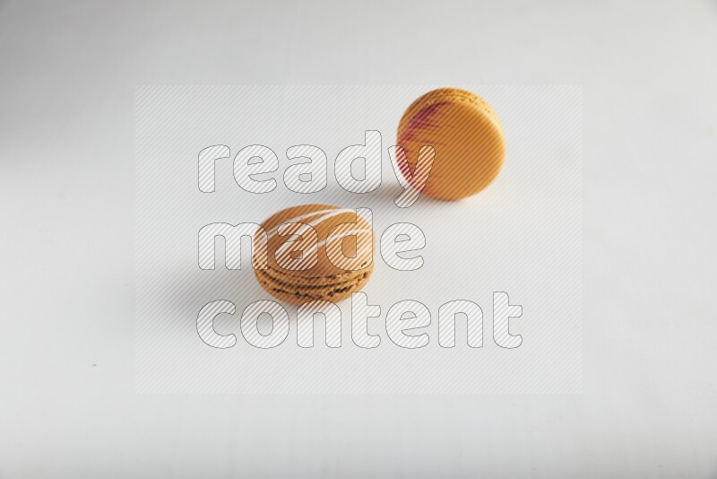 45º Shot of of two assorted Brown Irish Cream, and Orange Exotic macarons on white background