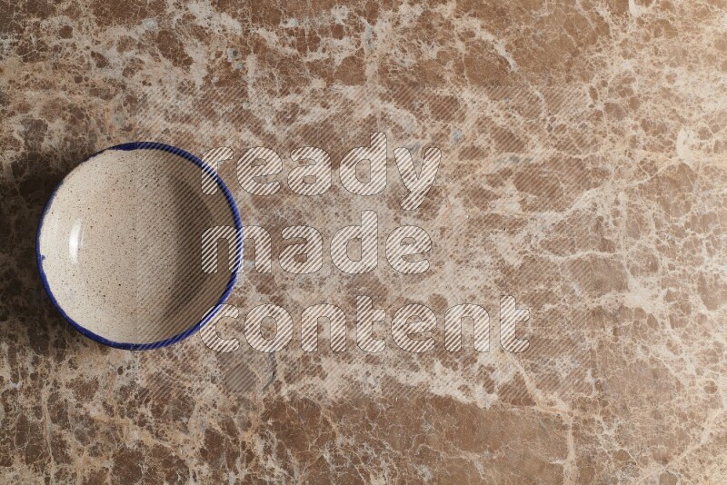 A multicolored pottery bowl on beige marble background