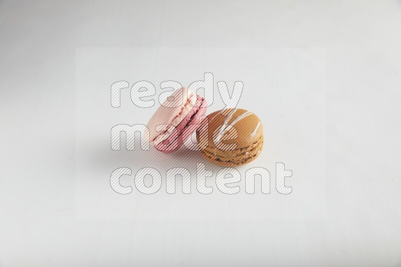 45º Shot of of two assorted Brown Irish Cream, and Pink Litchi Raspberry macarons on white background