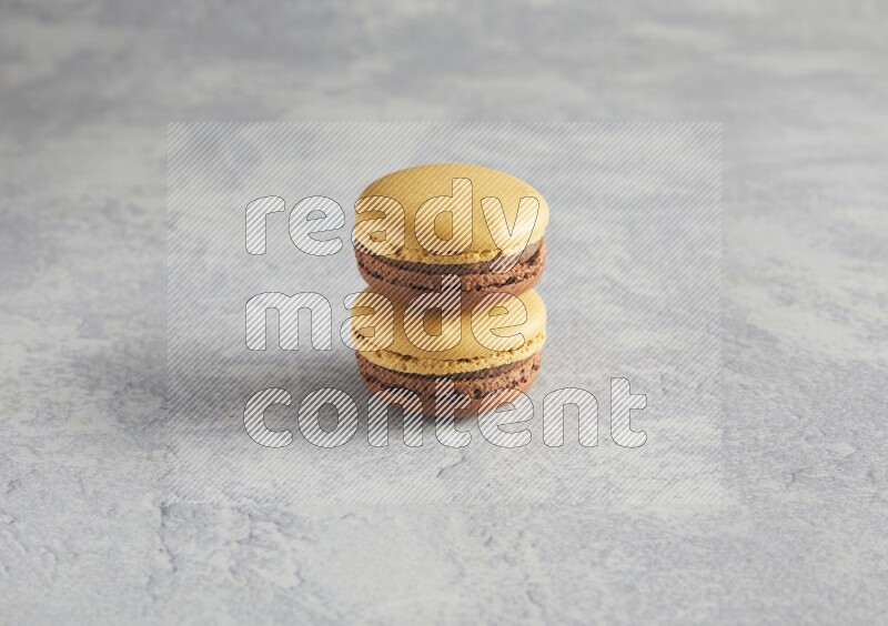 45º Shot of two Yellow and Brown Chai Latte macarons r on white  marble background