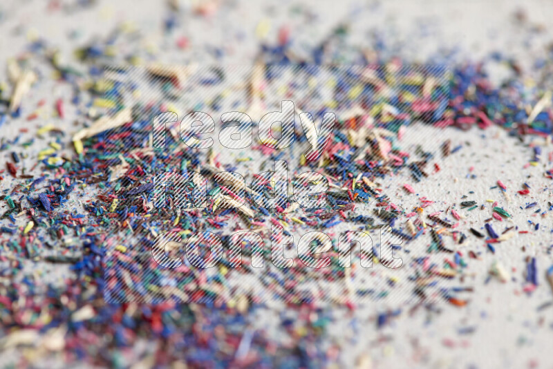 This image showcases a vibrant multicolored pencil shavings scattered on grey background