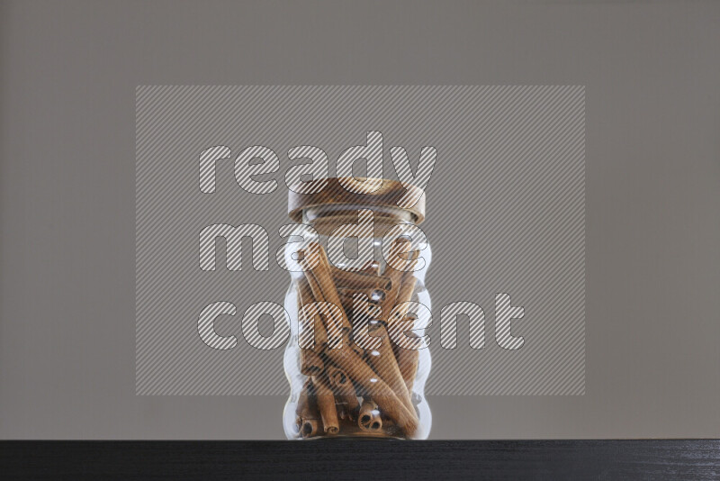 Cinnamon sticks in a glass jar on black background