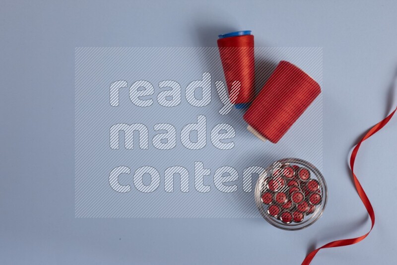 A red collection of sewing and tailoring tools arranged on a blue background