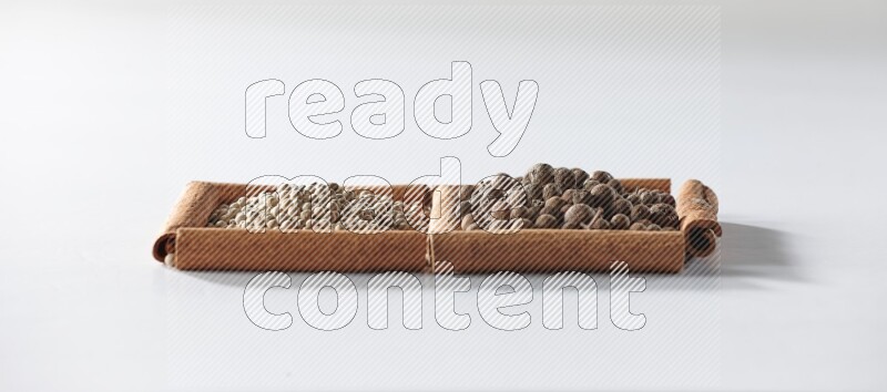 2 squares of cinnamon sticks full of white pepper and allspice on white flooring