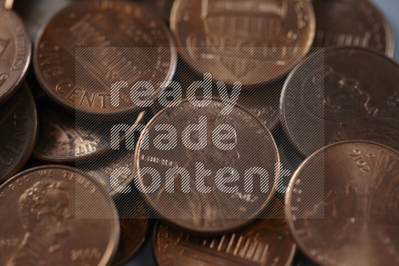 A close-up of scattered United States one cent coins on grey background