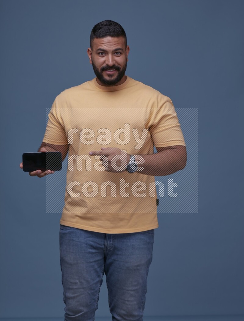 A man Showing His Smart Phone on Blue Background wearing Orange T-shirt