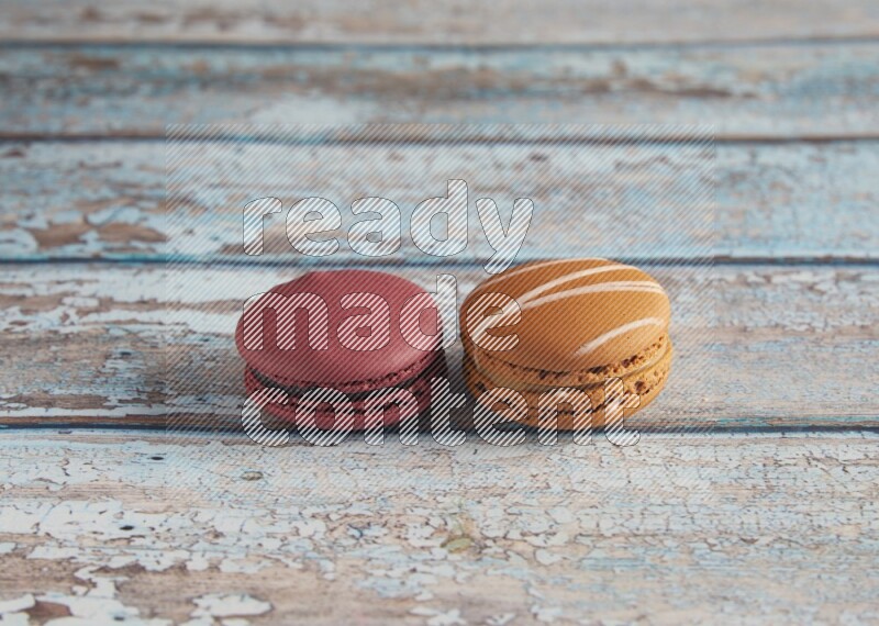 45º Shot of of two assorted Brown Irish Cream, and Red Cherry macarons  on light blue background