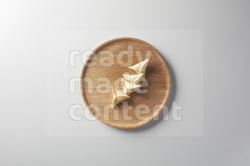 Four Sambosas on a wooden round plate on a white background