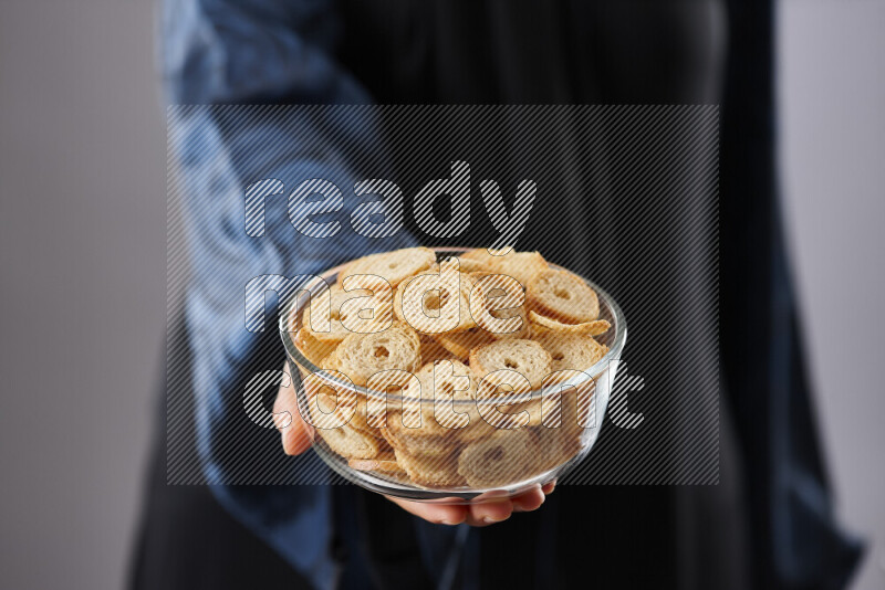 Woman in abaya holding different kinds of snacks in different positions