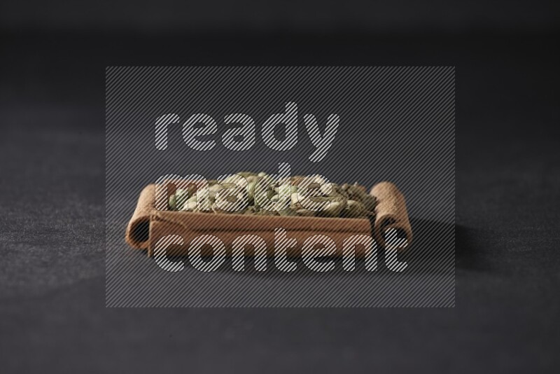 A single square of cinnamon sticks full of Cardamom on black flooring