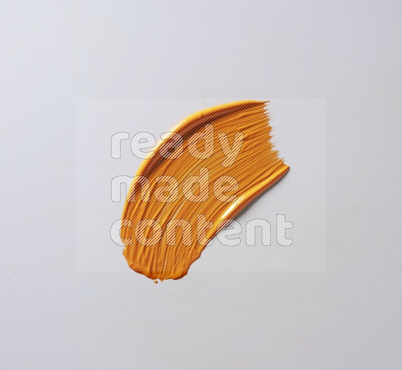 An orange curved painting brush stroke on a white background
