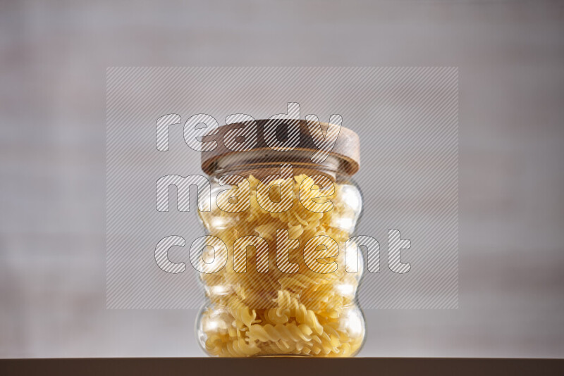 Raw pasta in glass jars on beige background