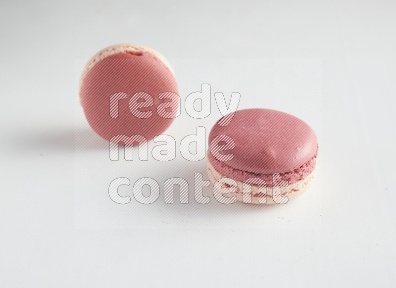 45º Shot of two Pink Litchi Raspberry macarons on white background