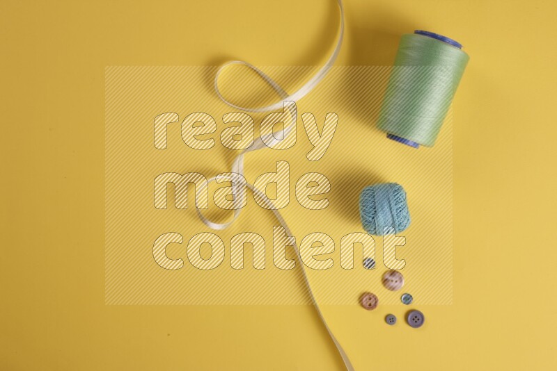 مجموعة من أدوات الخياطة والتفصيل خضراء اللون على خلفية صفراء