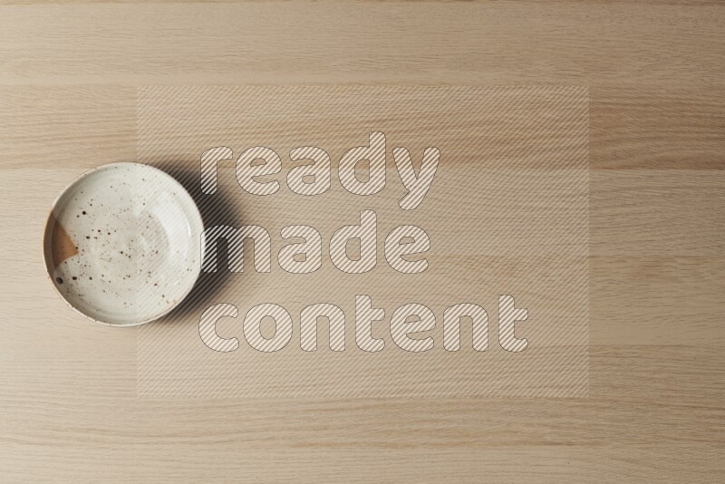 A multicolored pottery plate on light wooden background