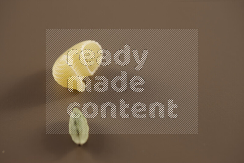 Raw pasta with different ingredients such as cherry tomatoes, garlic, onions, red chilis, black pepper, white pepper, bay laurel leaves, rosemary and cardamom on beige background