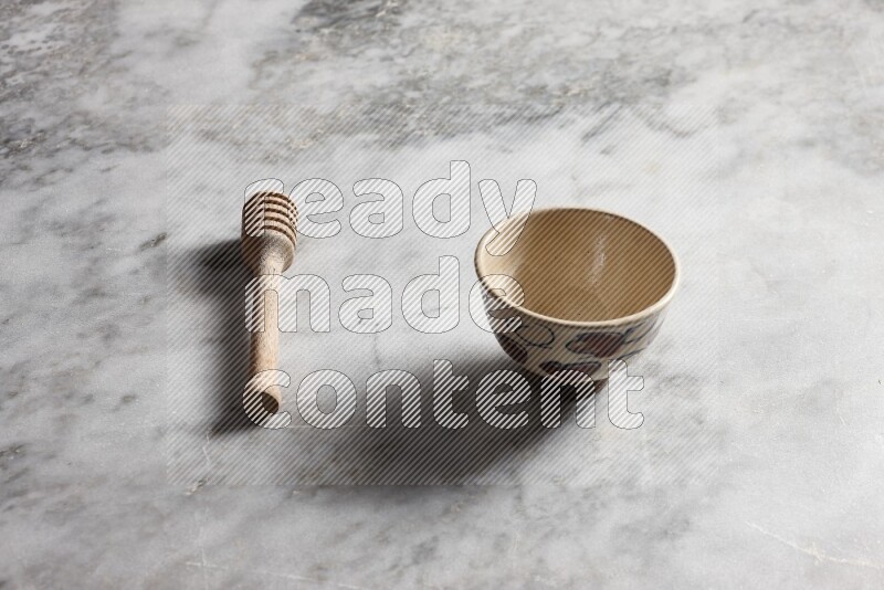 Decorative pottery bowl with wooden honey dipper on the side on grey marble background