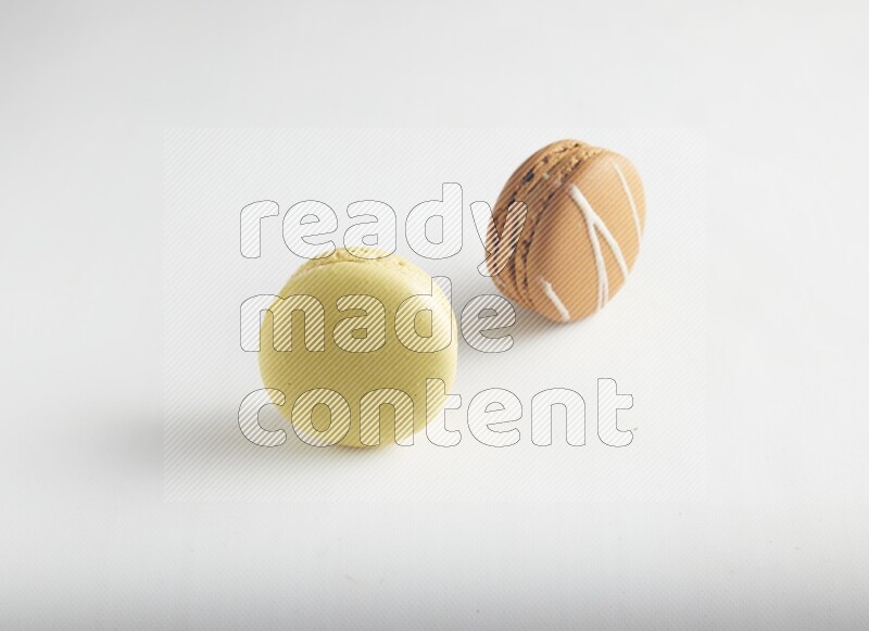45º Shot of of two assorted Brown Irish Cream, and Yellow Lime macarons on white background