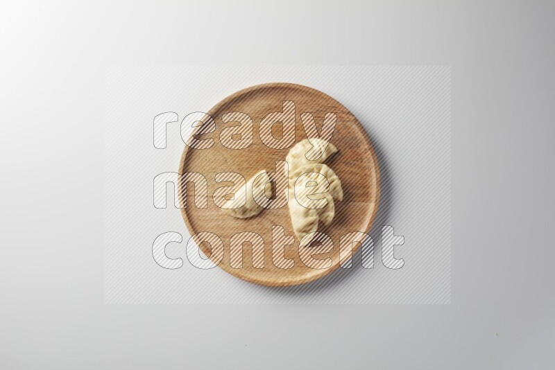 Five Sambosas on a wooden round plate on a white background