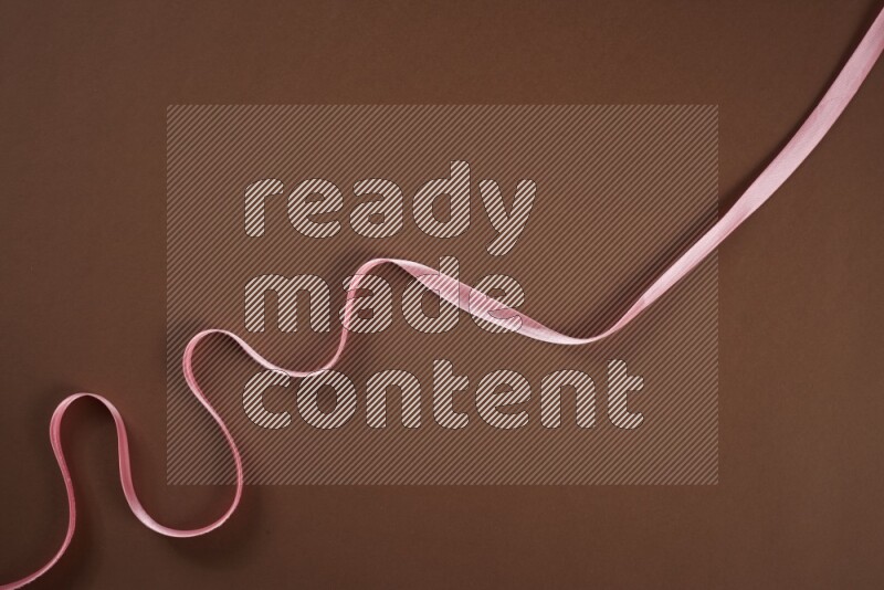 A pink collection of sewing and tailoring tools arranged on a brown background