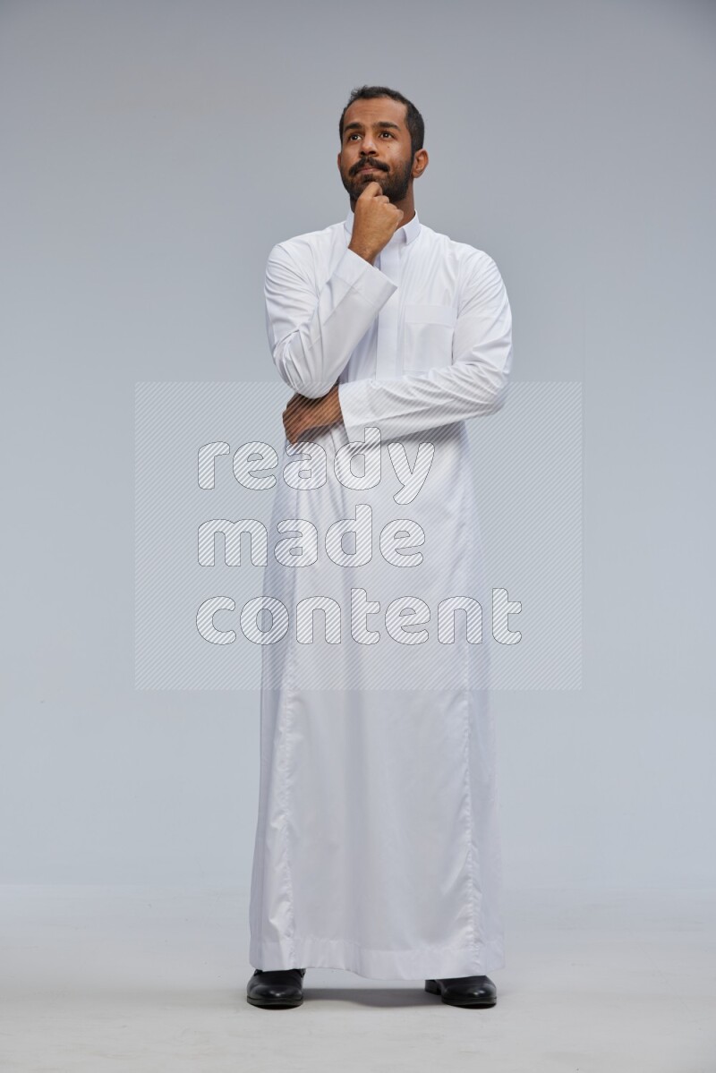 Saudi man Wearing Thob standing interacting with the camera on Gray background