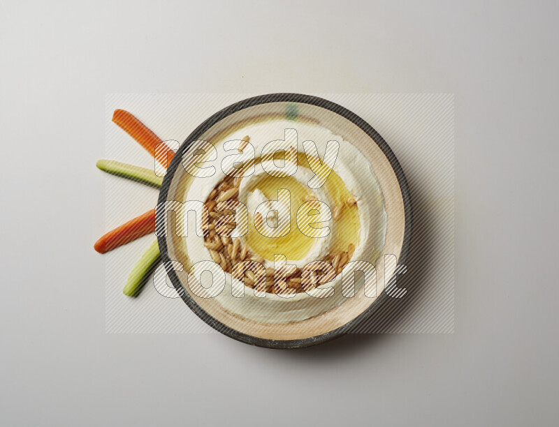 Lebnah garnished with pine nuts in a pottery plate on a white background