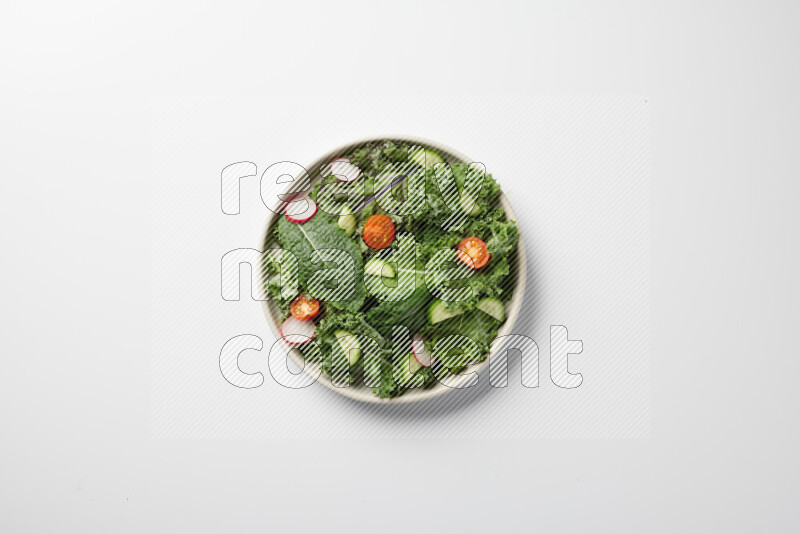 A bowl of fresh vegetables salad with kale leaves, cherry tomatoes, sliced radishes and sliced cucumber on a white background