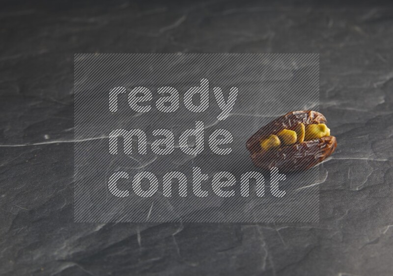 pistachios stuffed madjoul date on a black textured background