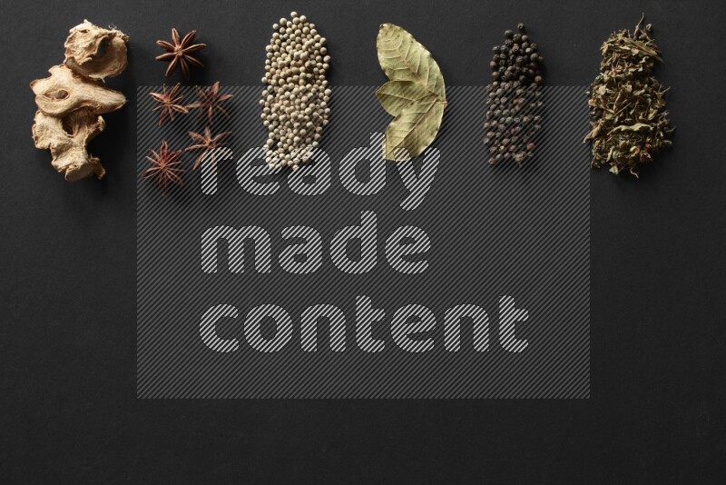 Ginger, star anise, white pepper, laurel bay leaves, black pepper and basil lined on a black background
