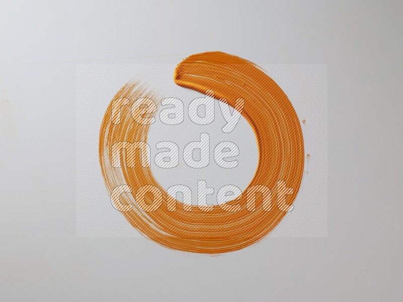 An orange circular painting brush stroke on white background