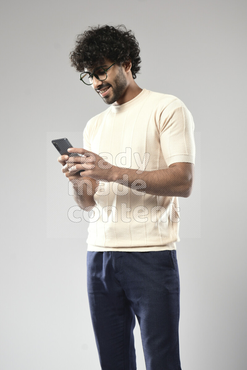 A man wearing casual standing and texting on the phone on white background