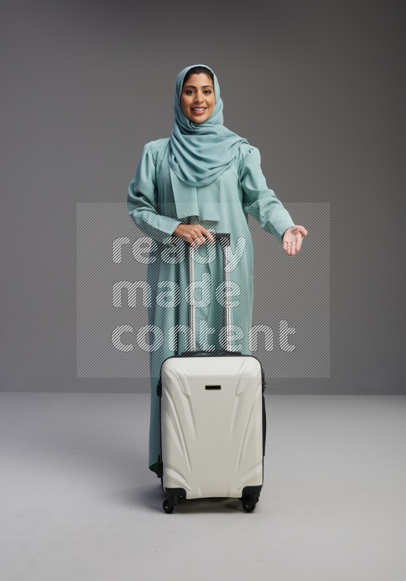 Saudi Woman wearing Abaya standing holding Travel bag on Gray background
