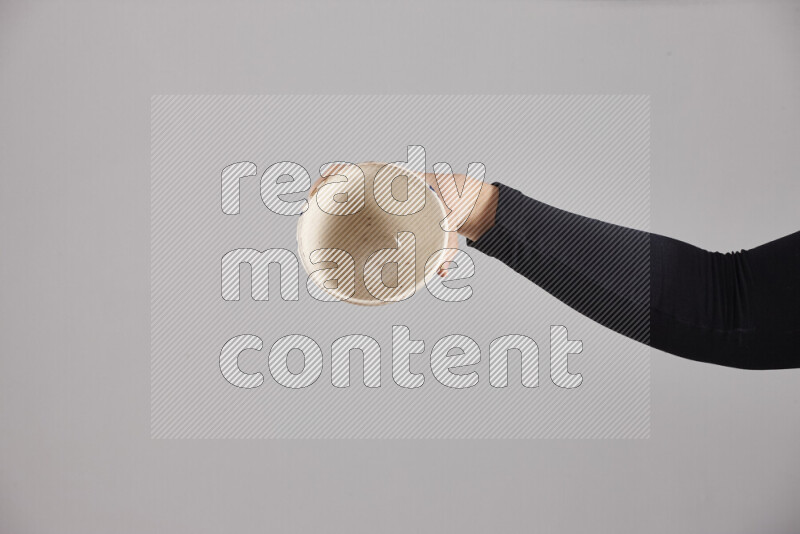 A woman in black abaya holding different pottery essentials in different positions