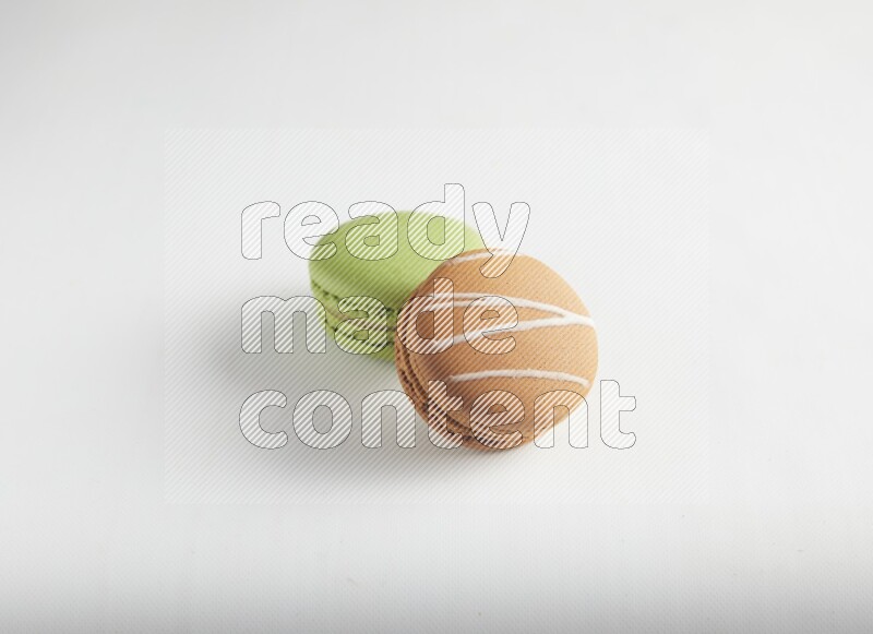 45º Shot of of two assorted Brown Irish Cream, and Green Pistachio macarons on white background