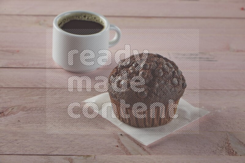 Chocolate cupcake topped with chocolate chips on a wooden pink background