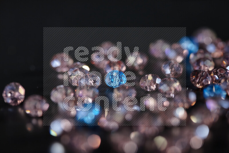 Rose and blue transparent crystal beads scattered on a black background