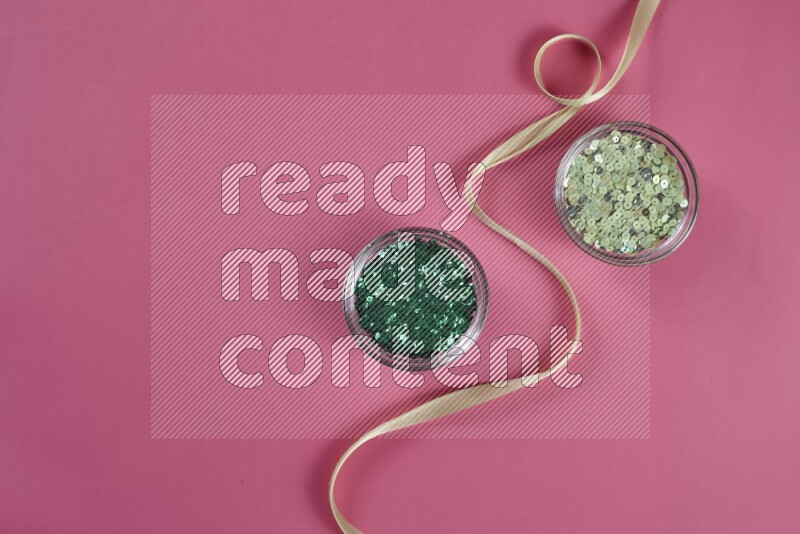 مجموعة من أدوات الخياطة والتفصيل خضراء وزهرية اللون على خلفية زهرية