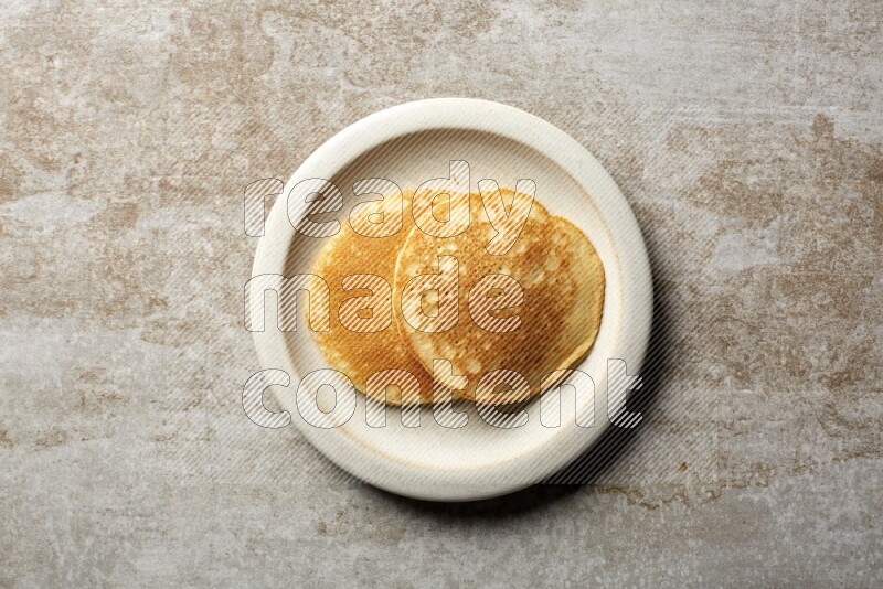 Two stacked plain pancakes in a beige plate on beige background