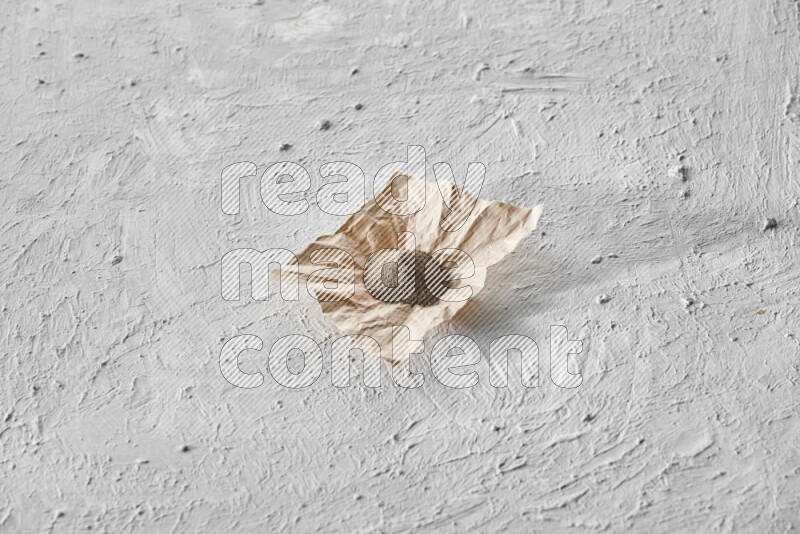 Black pepper powder on a crumpled paper on a textured white flooring
