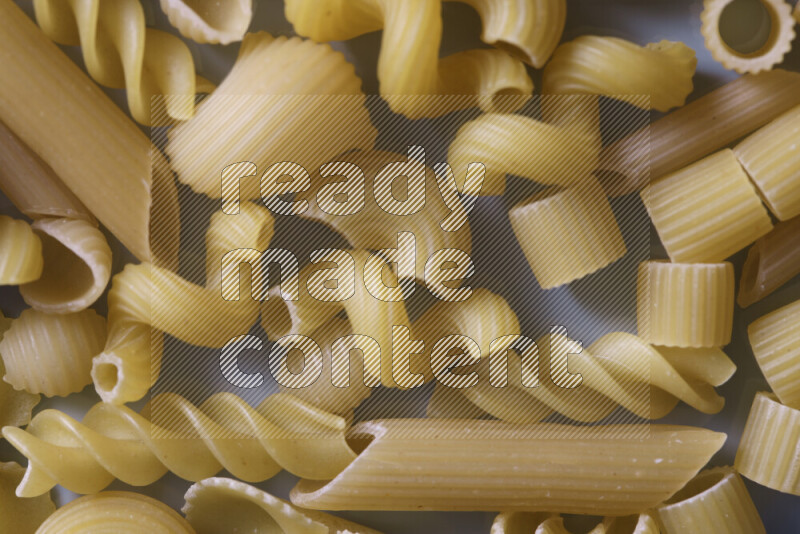 Different pasta types on light blue background