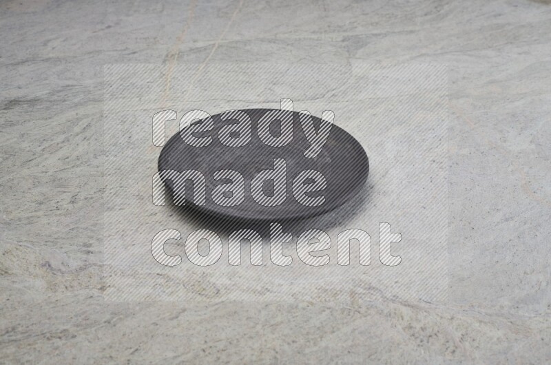 A black pottery plate on grey marble background