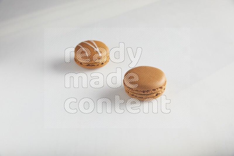 45º Shot of of two assorted Brown Irish Cream, and Brown Maple Taffy macarons  on white background